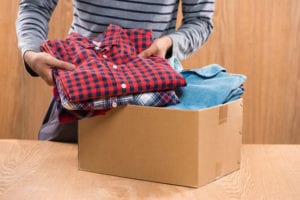 Man packing folded shirts into a cardboard box