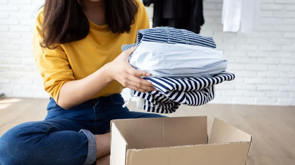 Donating Clothes Online A women packing some clothes for donation